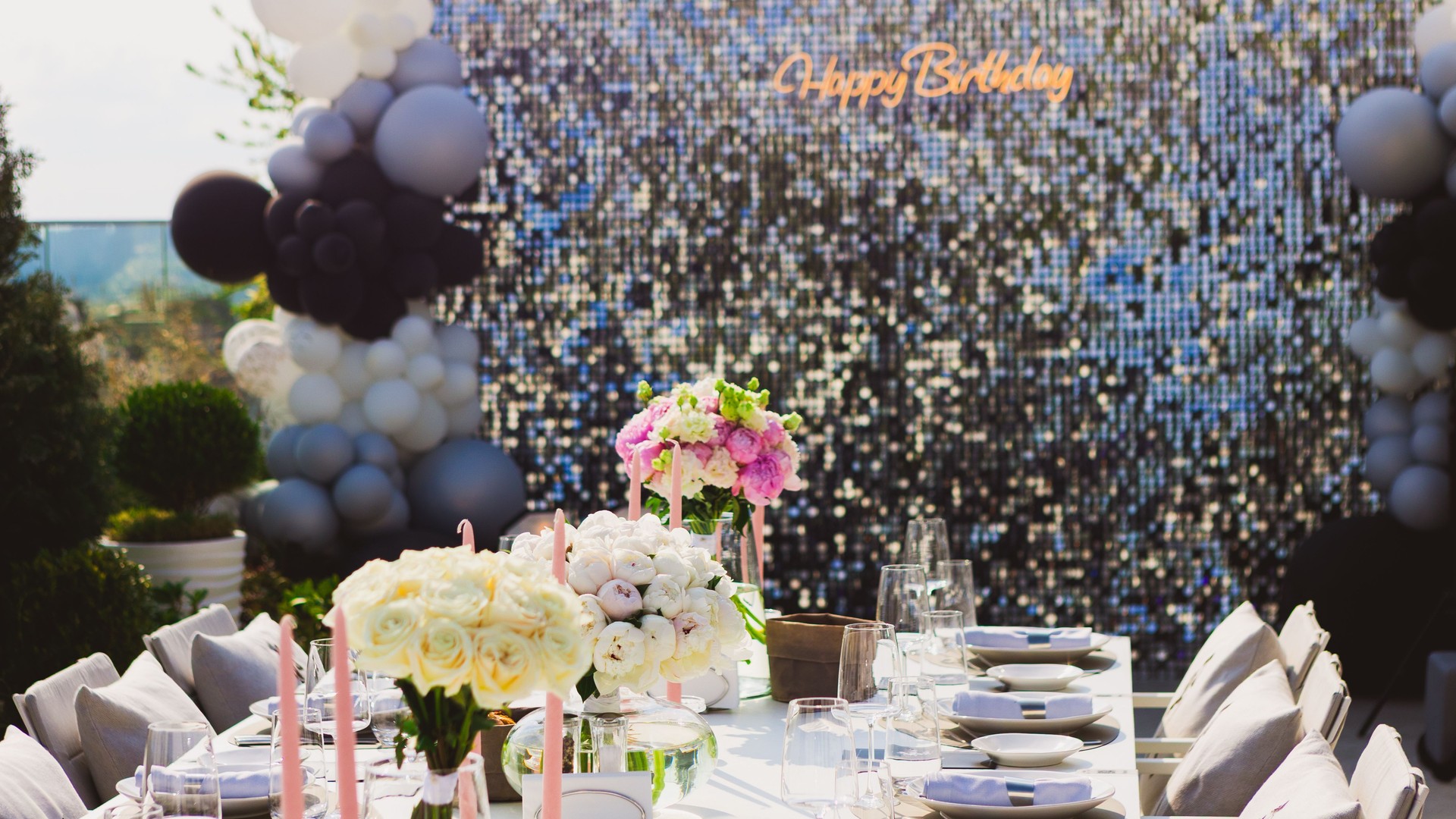 Featuring a dazzling sequin backdrop with a Happy Birthday neon sign, elegant table settings,