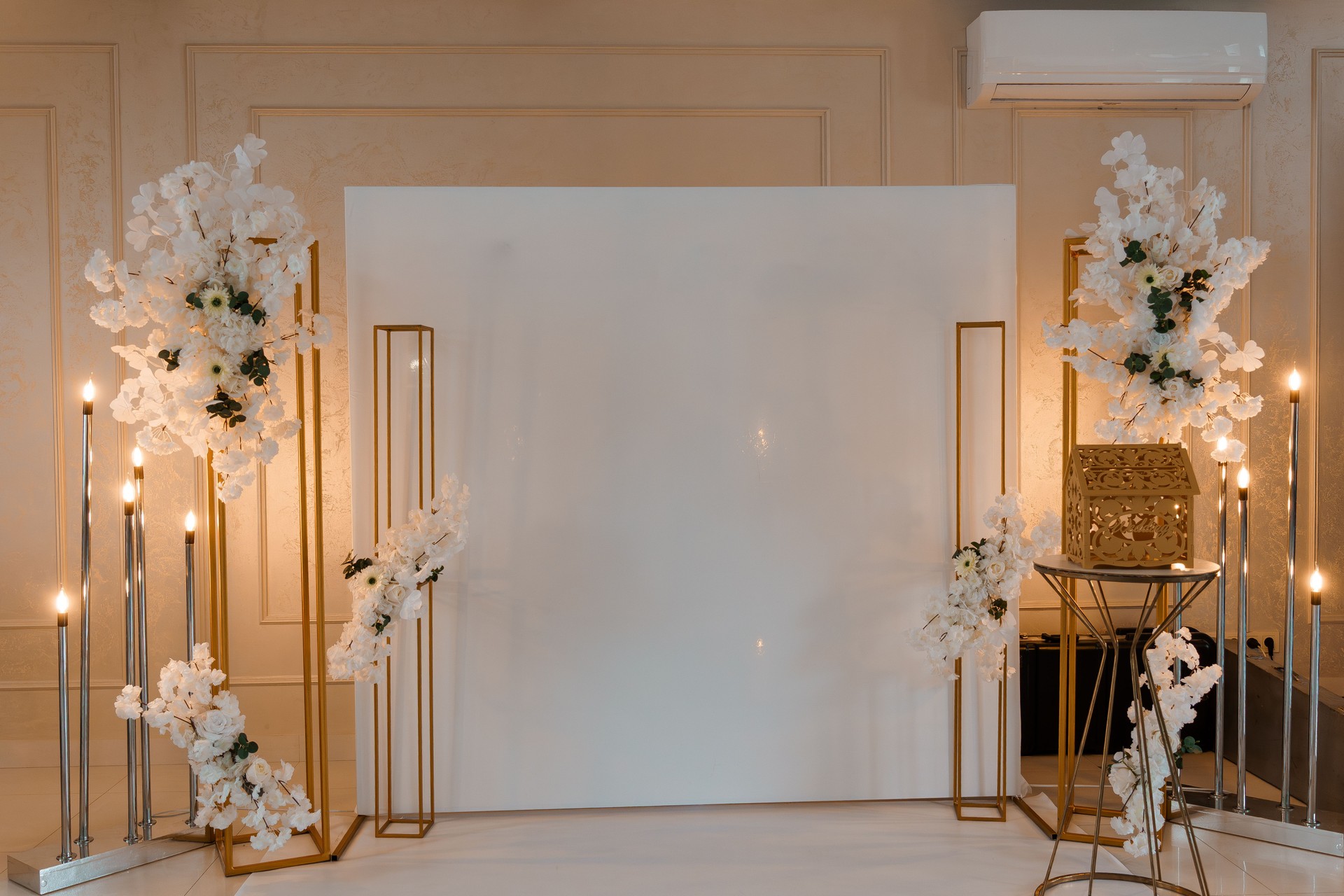 Elegant Wedding Backdrop with Floral Arrangements: Gold Frames, White Flowers, and Candlelight Ceremony Setting.