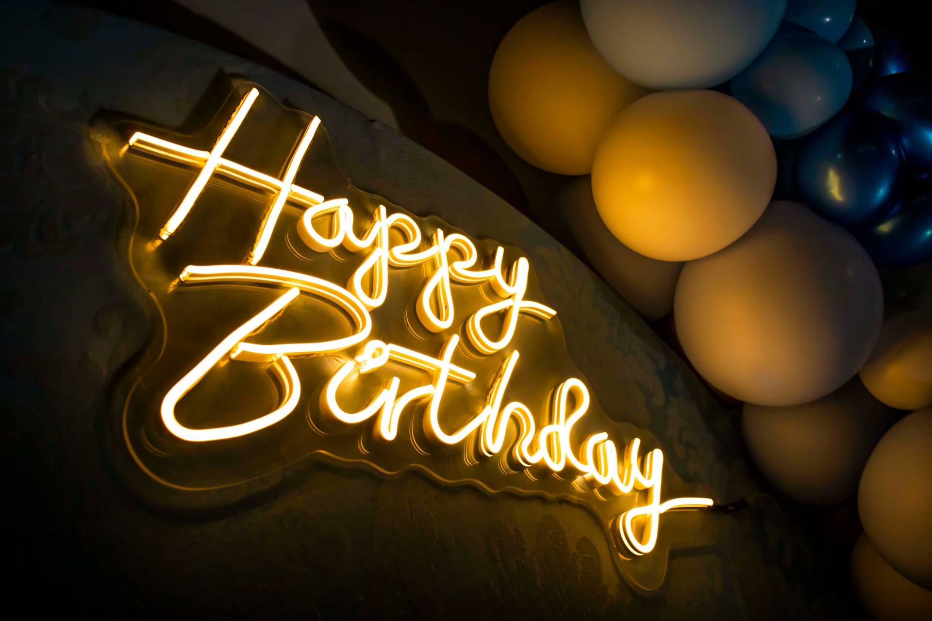 Happy birthday neon sign illuminating party atmosphere with balloons